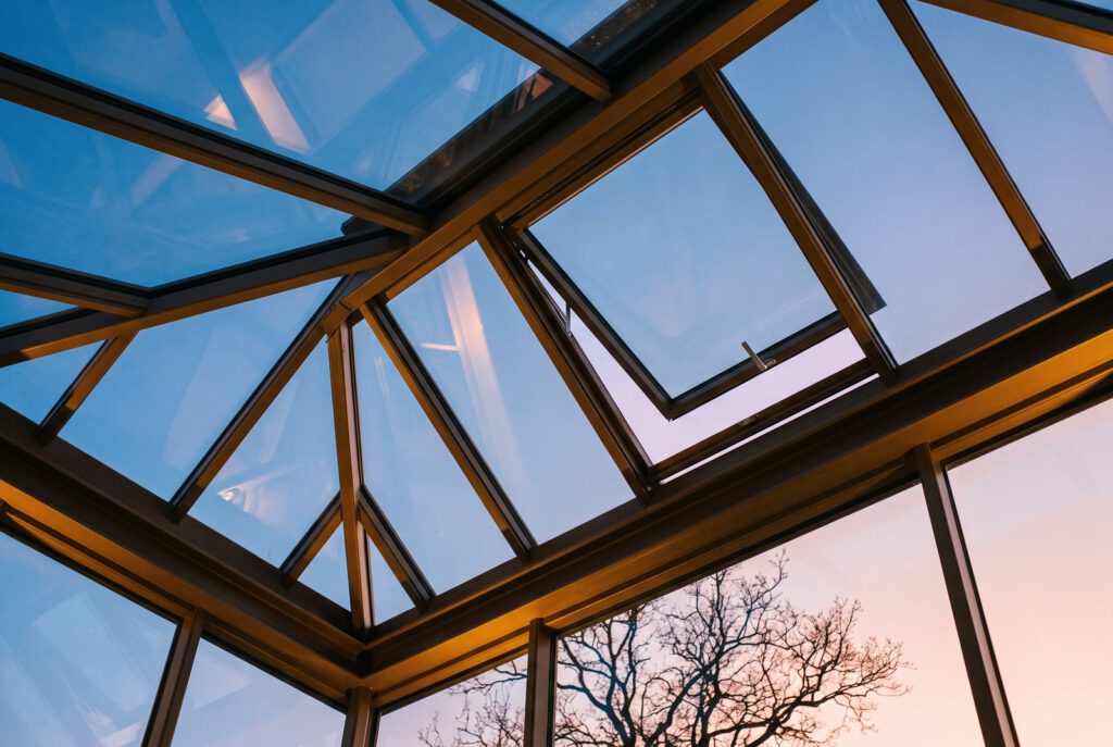 Glasdach mit Metallrahmen und geöffnetem Dachfenster im Abendlicht